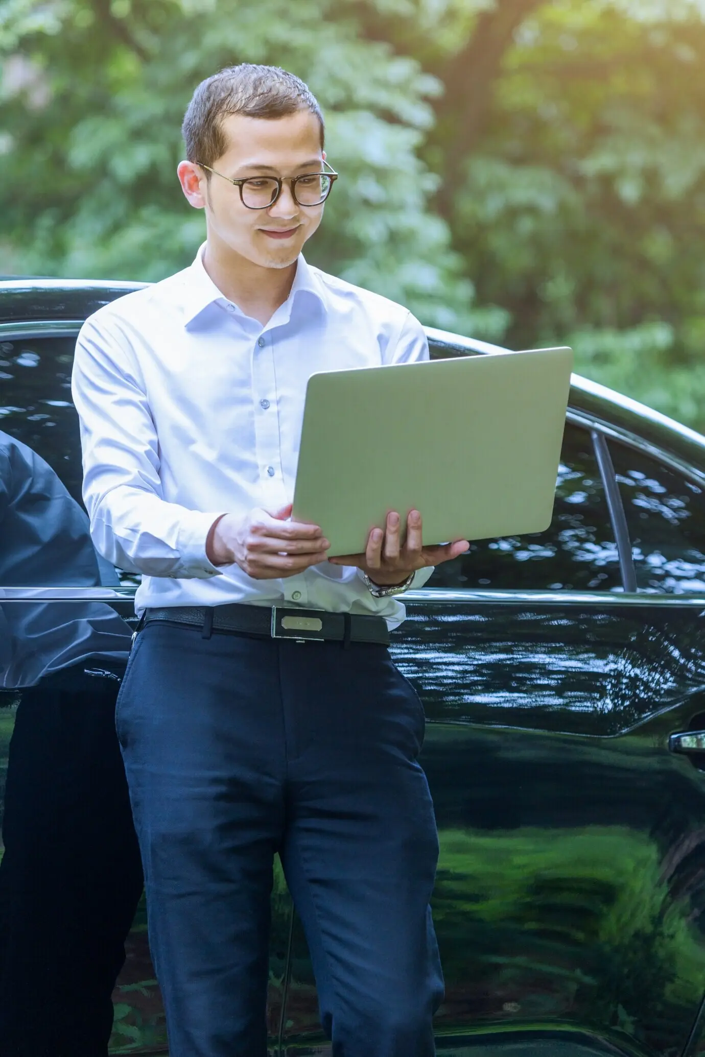 Деловые мужчины используют ноутбуки рядом с транспортными средствами на открытом воздухе.