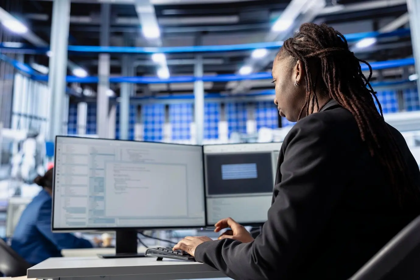 Инженер программирует за рабочей станцией на заводе по производству солнечных панелей.