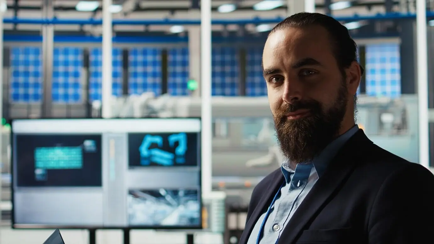 Мужчина на заводе по производству солнечных панелей использует ноутбук для повышения эффективности солнечных элементов.