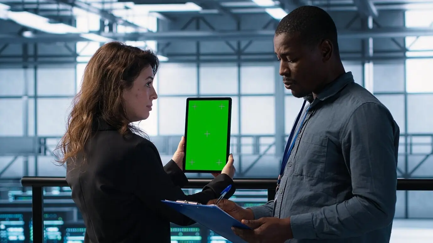 В дата-центре специалисты по информатике используют макет планшета при осмотре серверных стоек.